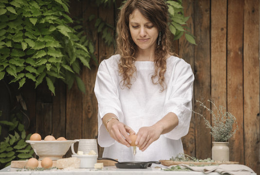 Woman standing by table, preparing eggs for breakfast