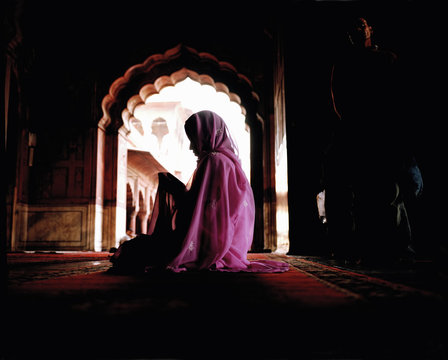 Woman wearing pink veil and sari sitting on floor 