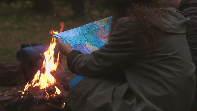 Hikers couple studying the map near bonfire. 4K UHD RAW edited footage