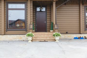 Vases with white flowers stand in the front of door entrance