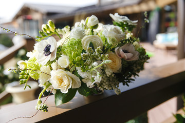 Tender white bouquet with greenery stands on wooden porch