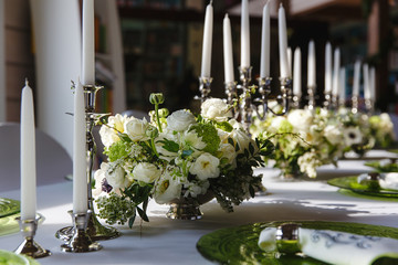 White candles in silver holders stand on the dinner tabe behind