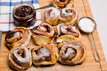 Homemade fresh baked yeast buns with plum jam. Sprinkled with icing sugar.