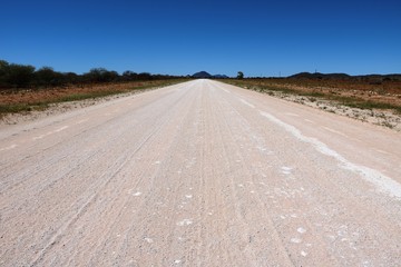 Dusty dirt road in Namibia under blue sky, Africa