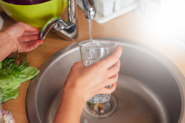 Woman hand's filling the glass of water