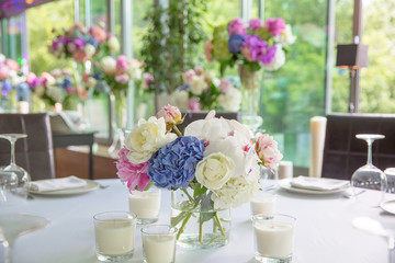 Blue, pink and white pionies stand in a little glass vase in the