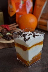Tiramisu with beautiful layers of white and orange colors.. Individual dessert in small glass cup on vintage table. You have gorgeous, party-worthy desserts without a lot of work!