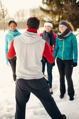 Group of friends stretching in the snow in winter