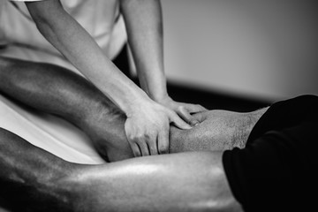 Sports massage. Massaging legs. Black and white