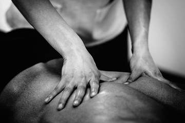 Sports massage. Massaging lower back. Black and white