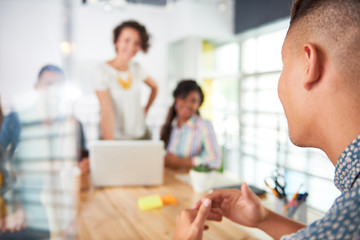 Multi ethnic group of succesful creative business people using a laptop during candid meeting