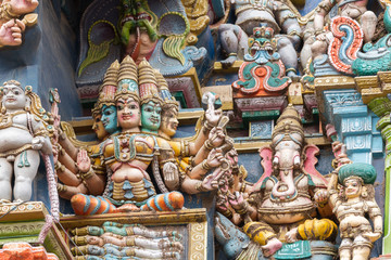 Naklejka premium Madurai, India - October 19, 2013: Closeup of goddess Gayatri sitting on coffin with the four Vedas inside. Ganesha keeps her company. Facade of West Gopuram at Meenakshi Temple.