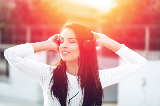 Young woman with headphones listening music in sunset