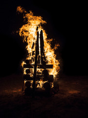 Fototapeta na wymiar Closeup of a large fire built of logs on a black background