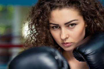 Woman in boxing gloves look at camera, ready to fight