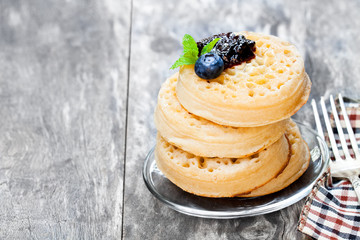 Hot  toasted crumpets on the wooden table with blueberries and j