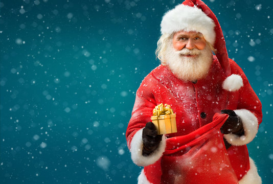 Happy Santa Claus with gift on blue background. Merry Christmas & New Year's Eve concept.