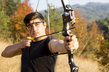 Archer drawing his compound bow trees