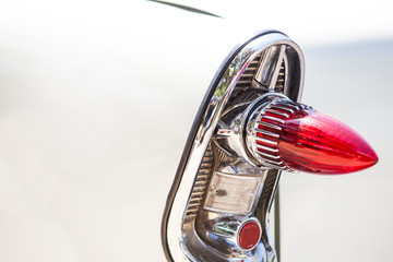 Part of a white old car with red headlamp