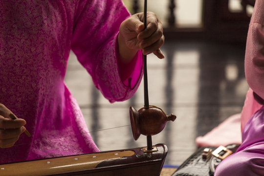 Woman play a typical vietnamese monochord musical instrument : the " dan bau " . Black and white picture