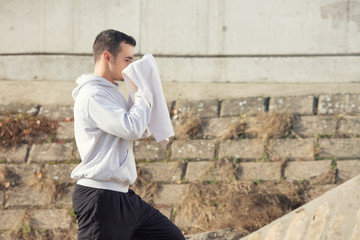 Youg man clearing his face using a towel.