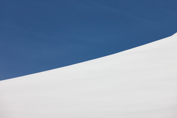 Abstract image of snow slope and blue sky border.