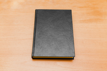 Book with black cover laying on wooden table