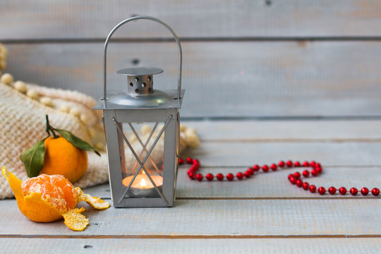 Christmas still life with lantern, plaid,  tangerine and red bea