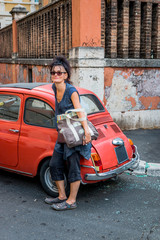 Femme devant une vieille voiture dans les rues de Rome