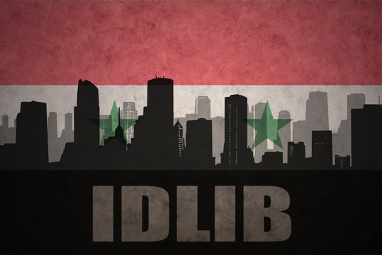 abstract silhouette of the city with text Idlib at the vintage syrian flag background