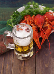 Glass of beer and a boiled crawfishes in a plate  on a wooden background, top view