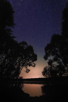 Beautiful night landscape on the forest lake with stars and refl