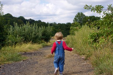 Naklejka na ściany i meble adorable young boy wearing overalls running on farm field