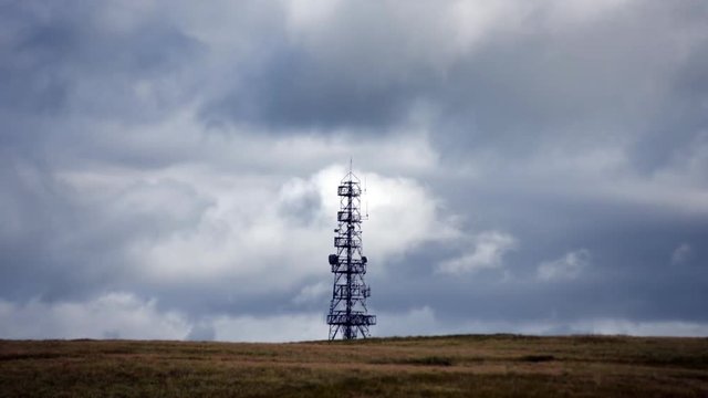 Time-lapse of antenna tower on a windy day with clouds passing by