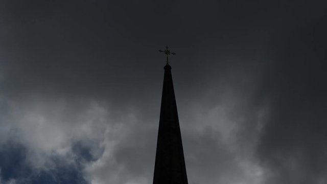 Time-lapse of church steeple against background of stormy clouds