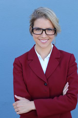 Attractive blonde woman with glasses crossing her arms confidently. All on blue background.