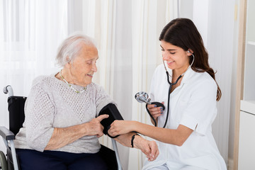 Female Doctor Checking Blood Pressure Of Senior Woman