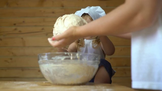 Mother kneading the dough for a bread with her little baby boy