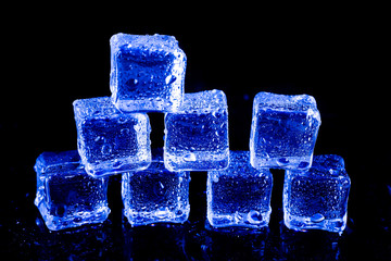 ice cubes in blue light on a black table.