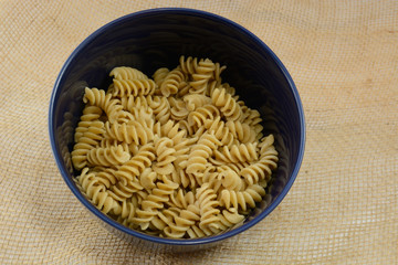 Boiled whole wheat rotini pasta in blue bowel as ingredient in casserole preparation