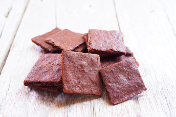 Close up of crunchy thin brownies on a wooden table.