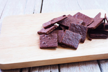Close up of a pile of crunchy wafer thin brownies on a wooden ta