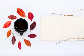 Open notepad with autumn falling leaves and cup of coffee