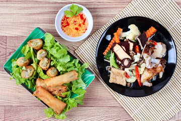 Fried big noodle topped mixed vegetables served deep fried spring roll for organic food . 