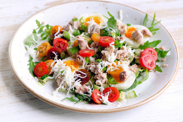 Fresh salad with fish, eggs and tomatoes in a plate.