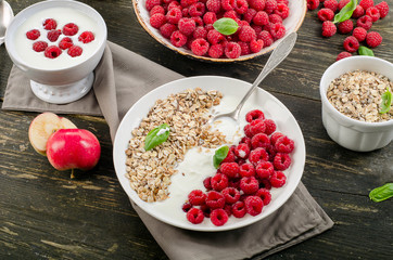 Muesli, yogurt and raspberries on a dark wooden background.
