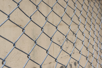Fence from steel mesh on grunge cement wall backgroud