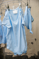 Baby laundry hanging on a clothesline and cement wall