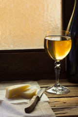 glass of white wine on a wooden surface with cheese on linen towel