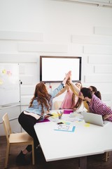 Happy executives giving high-five in meeting at creative office